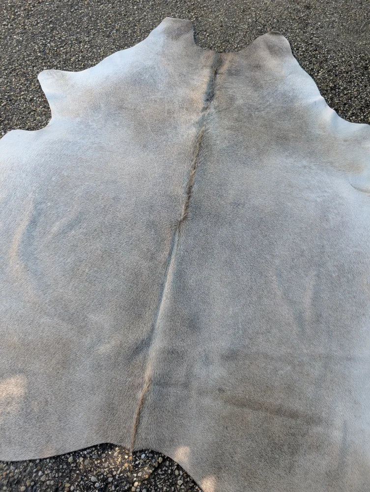 Large lovely grey cowhide rug with soft textured surface and visible stitching showcasing unique characteristics