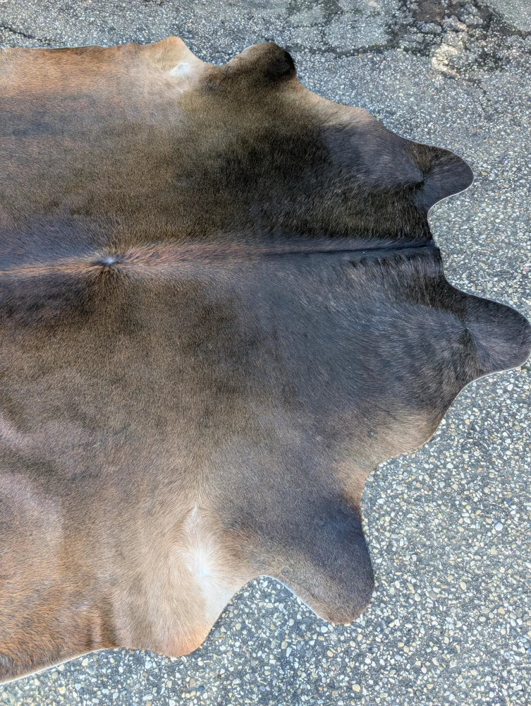 Large cowhide rug in brown and black with natural fur texture showing unique characteristics for stylish decor