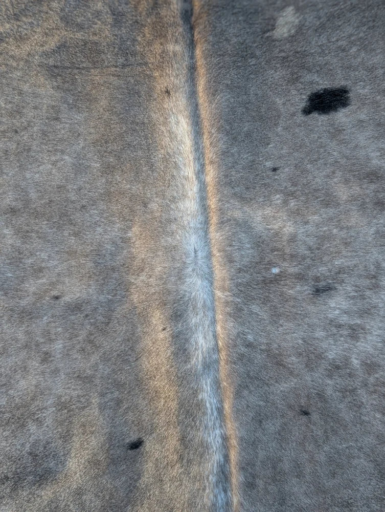 Gray faux fur large cowhide rug with central seam and subtle brownish highlights lovely cowhide rug unique characteristics