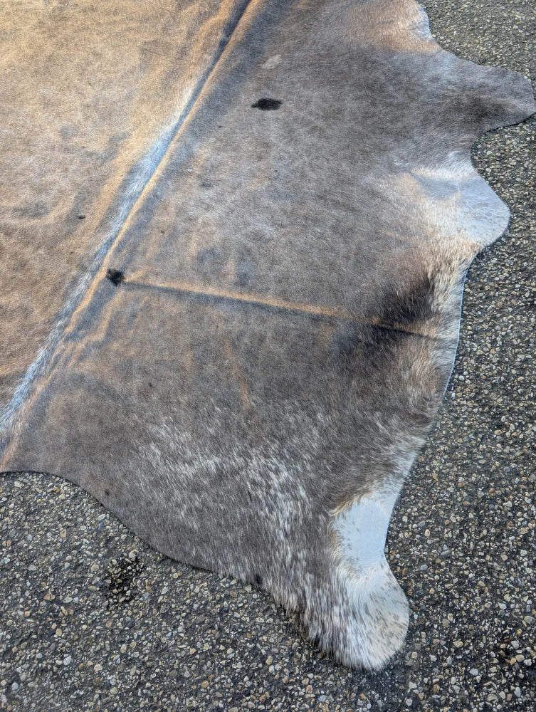 Large cowhide rug with unique characteristics featuring a lovely brown and gray mottled pattern in irregular shape