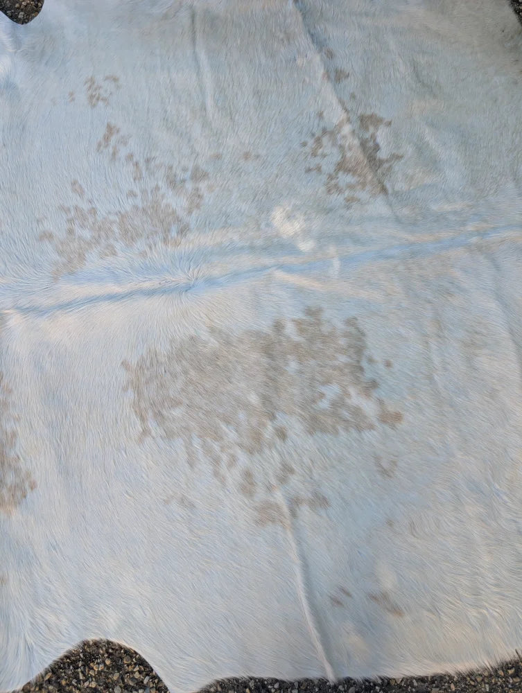 Large lovely cowhide rug featuring a white base with natural grayish-brown patches and unique characteristics