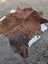 Brown and white large cowhide rug with natural fur texture showing unique characteristics in a lovely cowhide rug