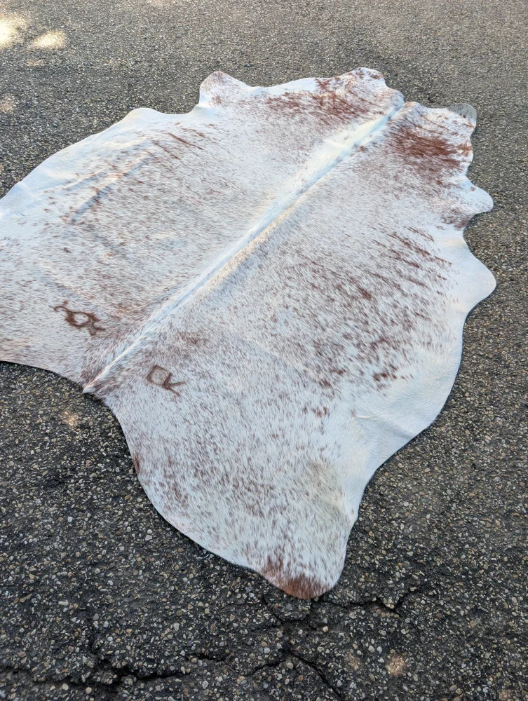 Large lovely cowhide rug with white and brown speckled pattern and unique natural irregular edges for a cozy look