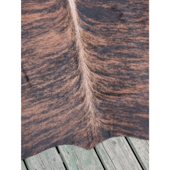 Brown and black large cowhide rug with unique characteristics and natural textured pattern measuring 66.5 by 63 inches