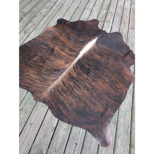Large cowhide rug t1 with rich brown and black textures and a natural white stripe perfect for adding unique characteristics