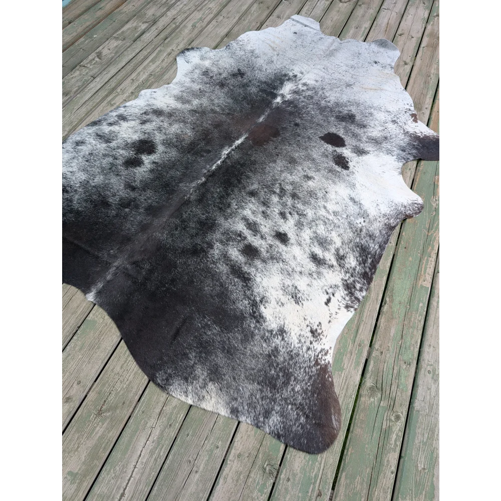 Large black and white cowhide rug with unique characteristics and natural dark patches over a lighter base