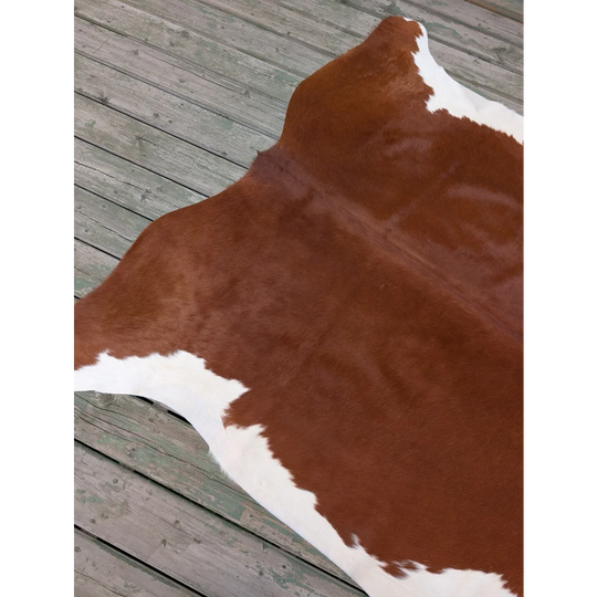 Large cowhide rug with brown and white natural irregular patches showcasing unique characteristics