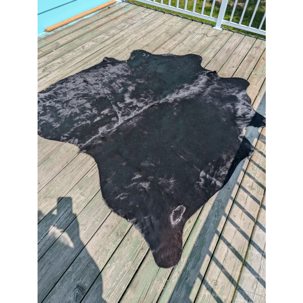 Large cowhide black cowhide rug with natural fur texture and subtle grayish-white markings by angus oliver