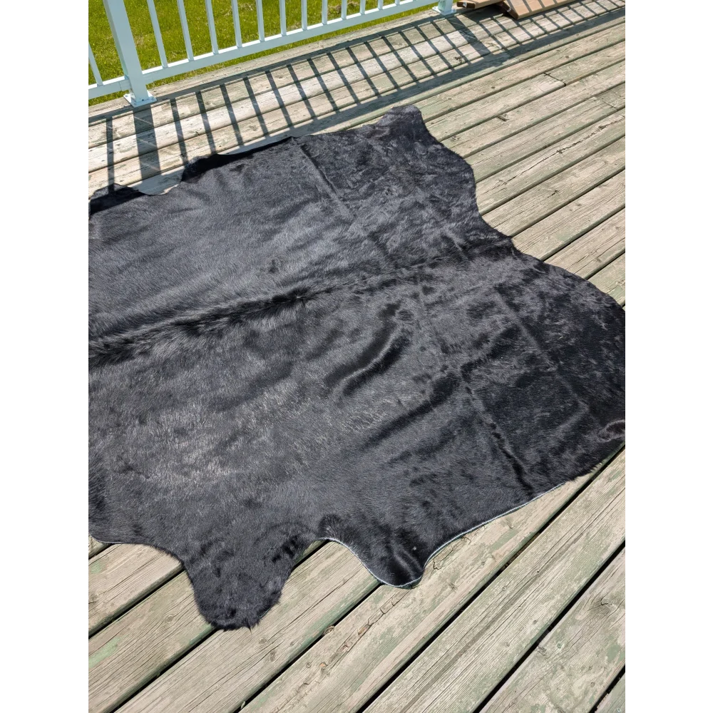 Large black cowhide rug with natural textured surface and irregular edges from angus oliver t14 75 x 69
