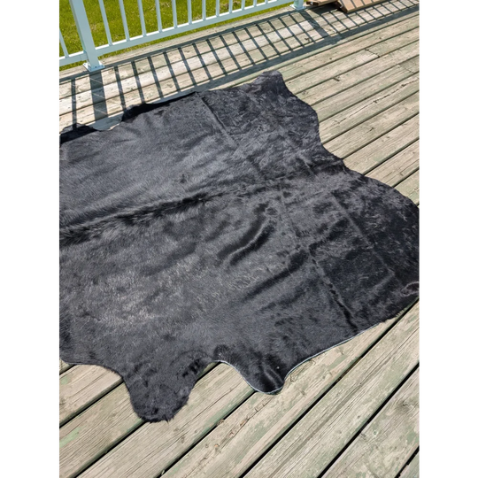 Large black cowhide rug with natural textured surface and irregular edges from angus oliver t14 75 x 69