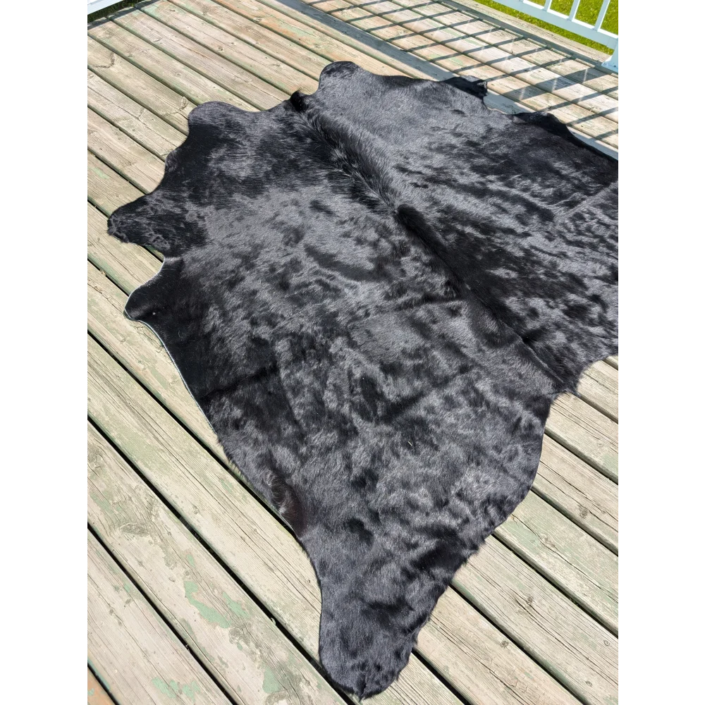 Large black cowhide rug with natural textured surface and irregular edges by angus oliver perfect for home decor