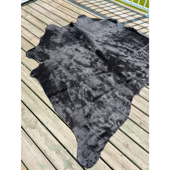 Large black cowhide rug with natural textured surface and irregular edges by angus oliver perfect for home decor