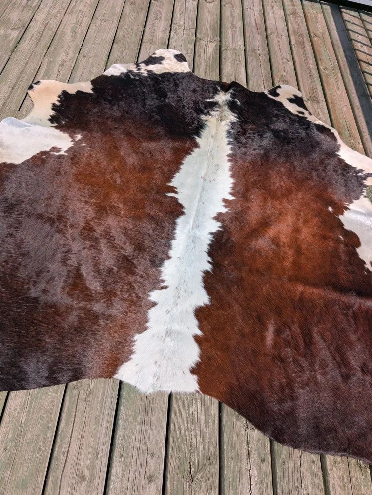 Large cowhide rug angus oliver with natural irregular brown and white pattern measuring 74 by 65 inches