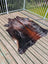 Large cowhide rug 78 x 64 with irregular shape and mottled dark brown black warm orange brown patches angus oliver