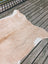 Tan and white large cowhide rug with natural pattern laid on weathered wooden planks angus oliver T18 77 x 63