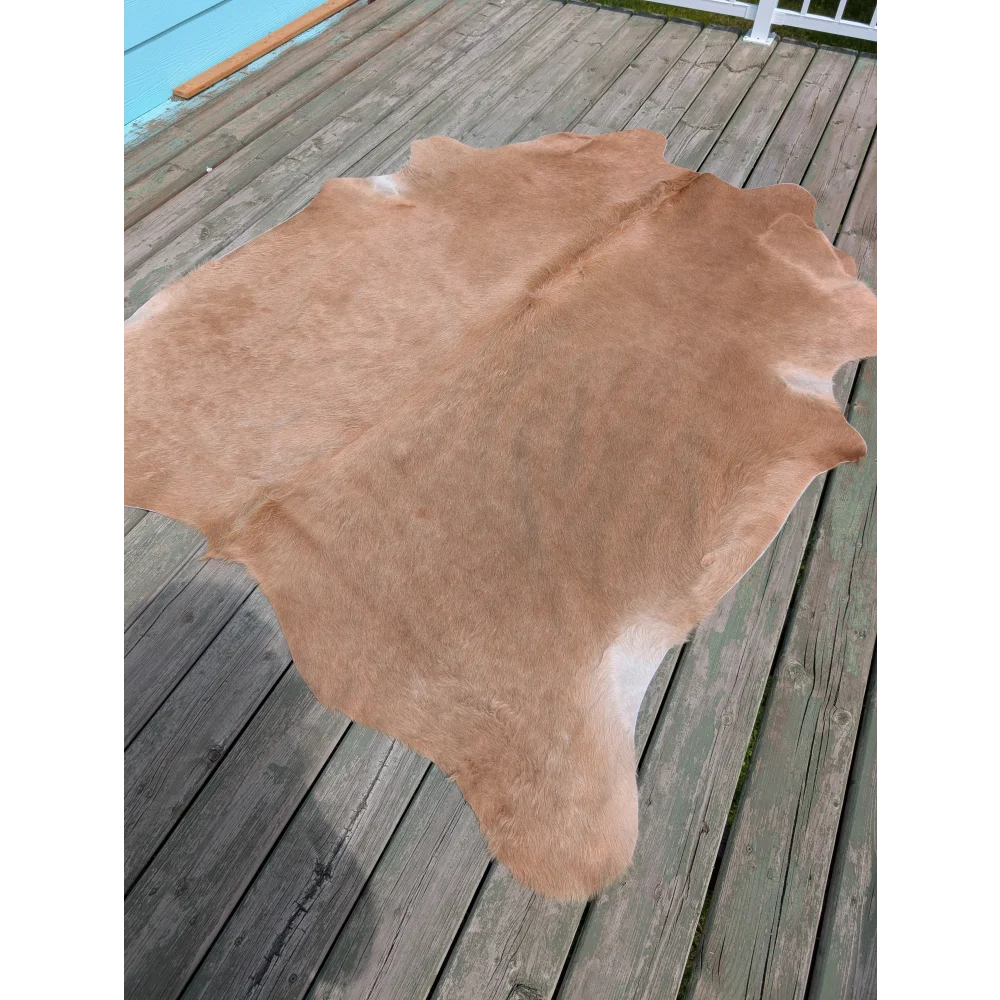 A large tan cowhide rug with natural texture and fluffy surface perfect for stylish spaces by angus oliver