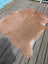 A large tan cowhide rug with natural texture and fluffy surface perfect for stylish spaces by angus oliver