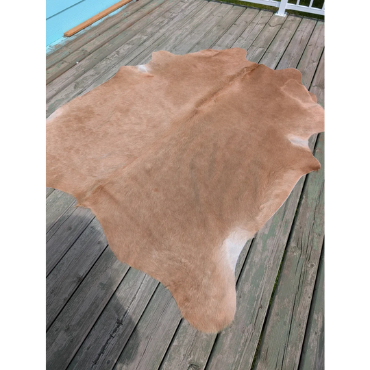 A large tan cowhide rug with natural texture and fluffy surface perfect for stylish spaces by angus oliver