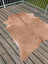Tan large cowhide rug with natural fur texture and irregular edges laid flat on wooden deck angus oliver T 19