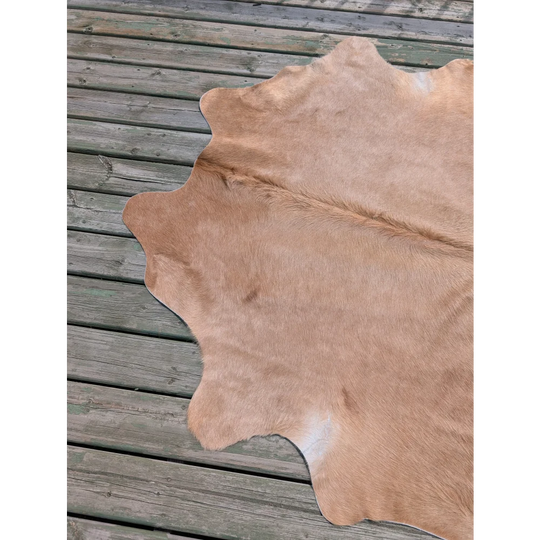 Tan large cowhide rug with natural fur texture and irregular edges perfect for angus oliver style decor