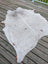 Large cowhide rug with white and brown speckled pattern and natural irregular edges showcasing unique characteristics