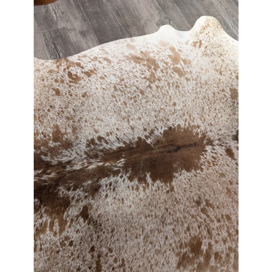 A large cowhide rug t21 72 x 62 with white and brown spots and a natural textured surface by angus oliver