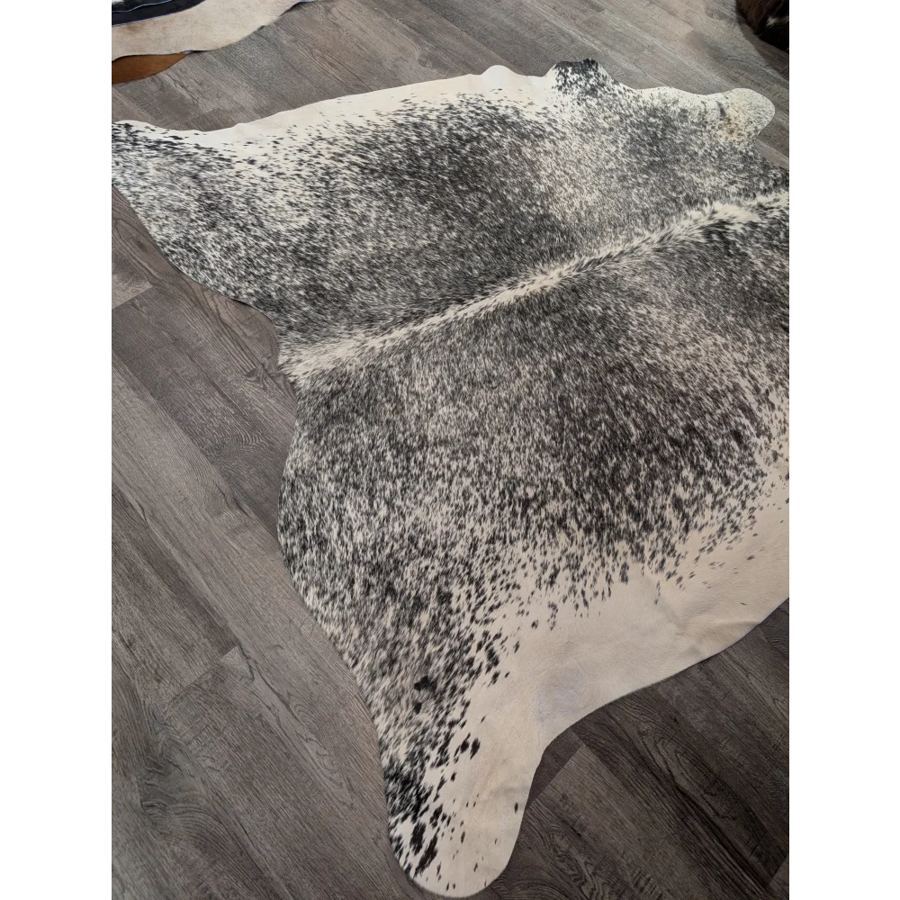 Large cowhide angus oliver cowhide rug with natural black and white speckled pattern on gray wood floor