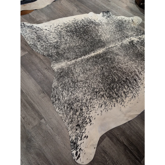 Large cowhide angus oliver cowhide rug with natural black and white speckled pattern on gray wood floor