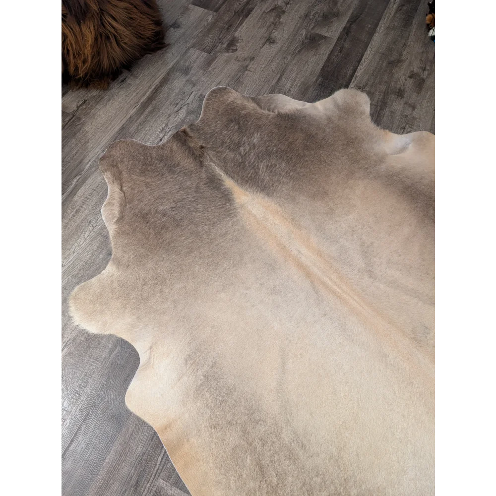 Large cowhide rug in natural tones with soft fluffy texture and irregular edges perfect for cozy spaces angus oliver