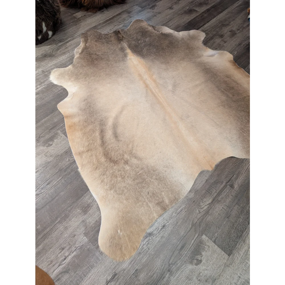 Large tan and beige natural cowhide rug by angus oliver with soft textured surface perfect for cozy spaces