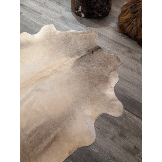 Large cowhide rug angus oliver with natural beige and brown tones and soft textured surface measuring 71 x 62 inches