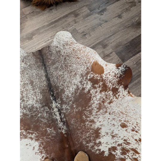 Large brown and white spotted cowhide rug with natural irregular edges by angus oliver perfect for home decor