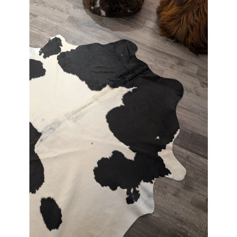 Large cowhide angus oliver cowhide rug with natural irregular black and white patches measuring 67.5 by 64 inches