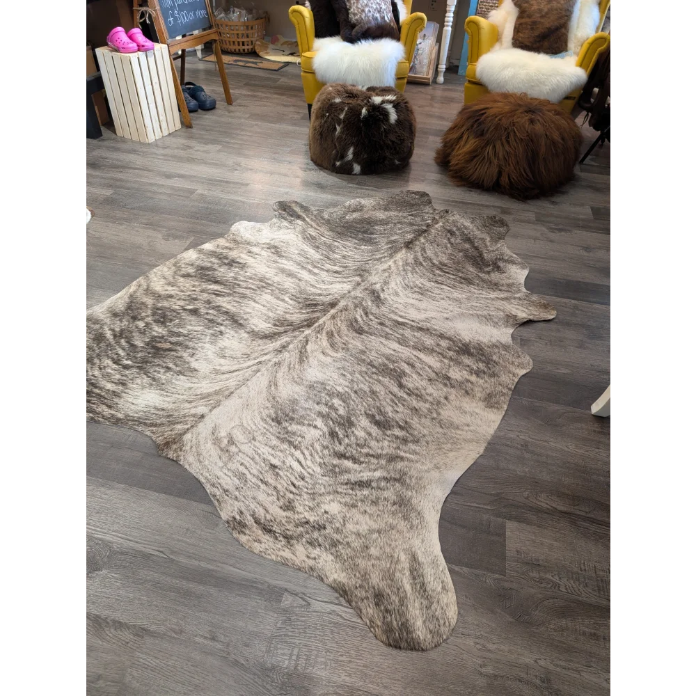 Natural-toned large cowhide rug with irregular shape and gray and white mottled fur by angus oliver