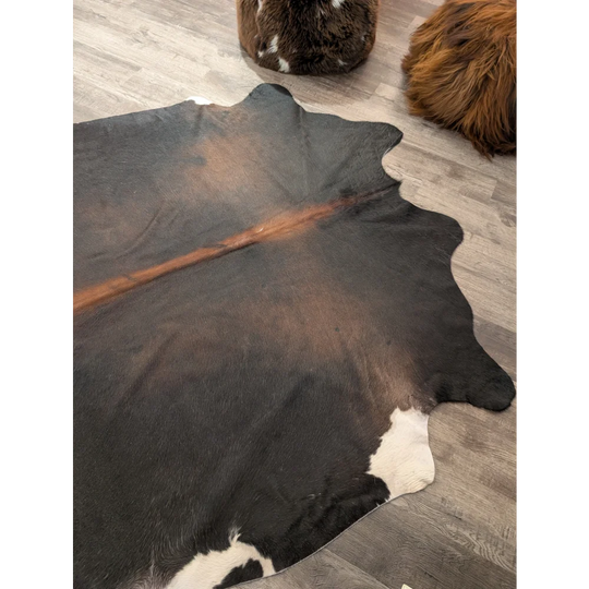 T27 large cowhide rug with natural black and white pattern and a bold brown stripe by angus oliver