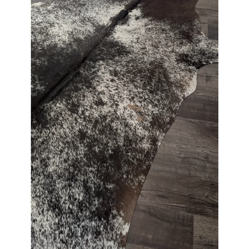 Large angus oliver cowhide rug in black and white speckled pattern laid on dark wood floor for stylish spaces