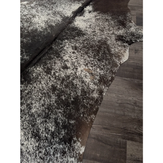 Large angus oliver cowhide rug in black and white speckled pattern laid on dark wood floor for stylish spaces