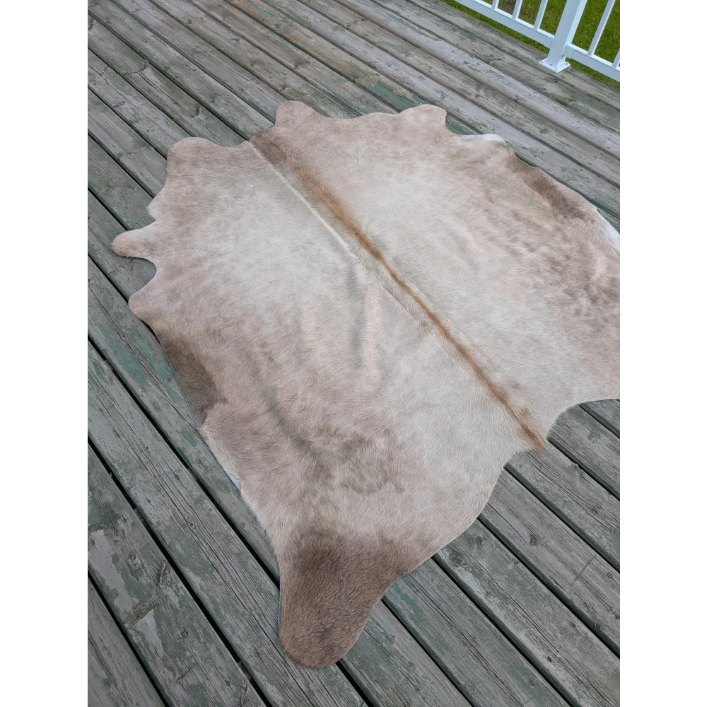 A natural-toned, full-sized cowhide rug with a soft, textured surface and subtle brownish patches.