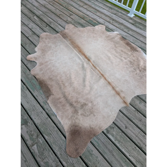 A natural-toned, full-sized cowhide rug with a soft, textured surface and subtle brownish patches.