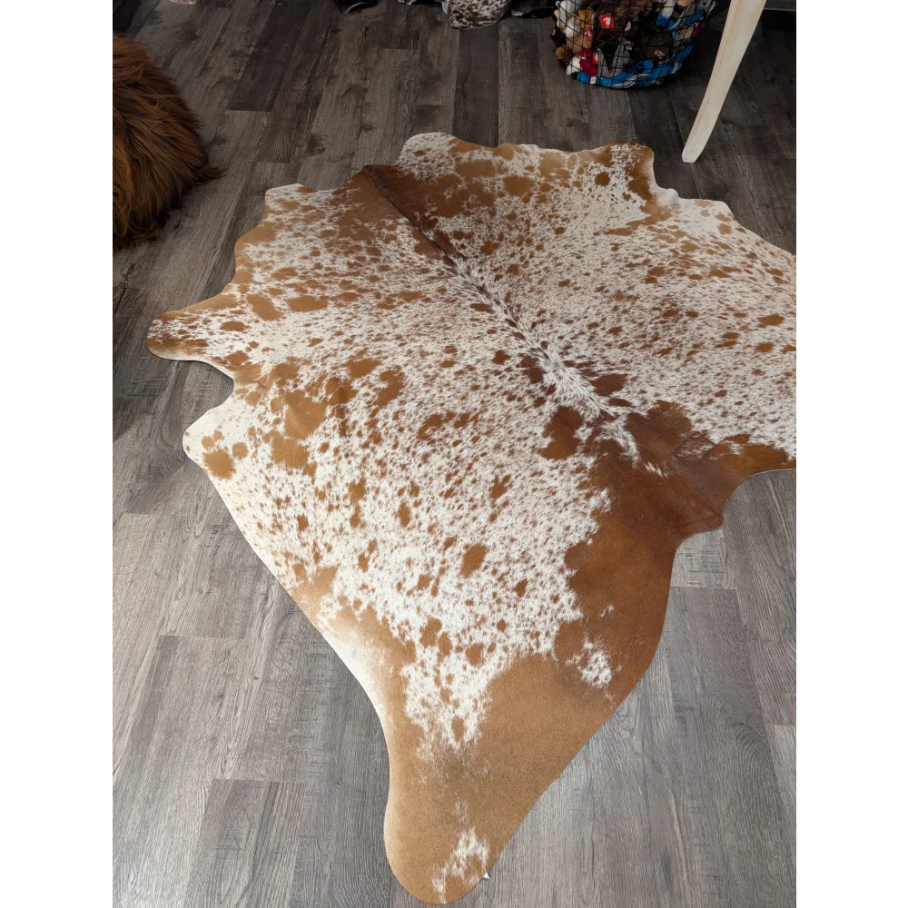 Large cowhide rug angus oliver with brown and white speckled pattern and natural irregular edges measuring 67 x 68 inches