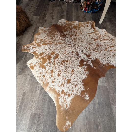 Large cowhide rug angus oliver with brown and white speckled pattern and natural irregular edges measuring 67 x 68 inches
