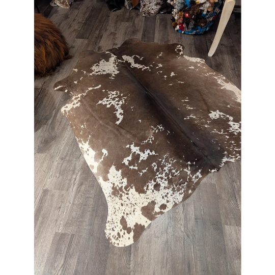 Large cowhide rug in brown and white spotted angus oliver design measuring 72 by 62 inches