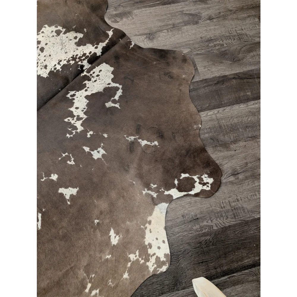 Large cowhide rug from angus oliver featuring brown and white natural irregular patterns measuring 72 by 62 inches