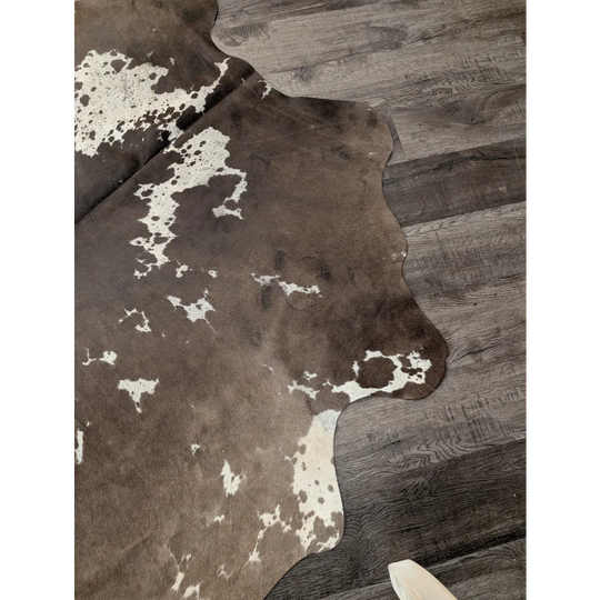 Large cowhide rug from angus oliver featuring brown and white natural irregular patterns measuring 72 by 62 inches