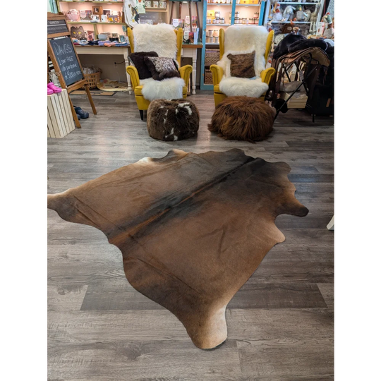 Large brown angus oliver cowhide rug with natural irregular edges and soft textured surface measuring 77 x 66 inches