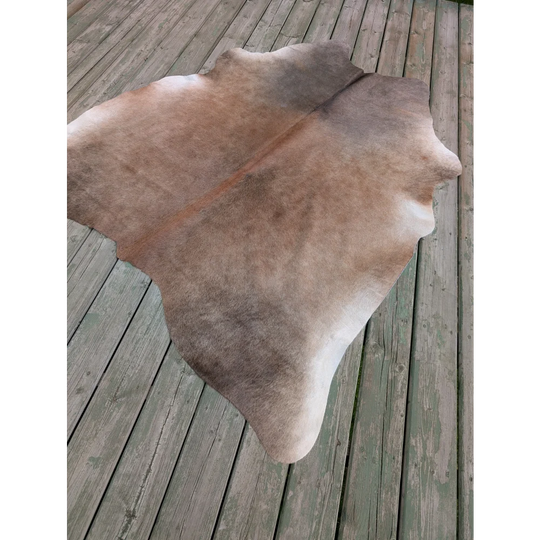 Large cowhide rug t5 73 x 64 with natural brown and white colors and unique characteristics on wooden planks