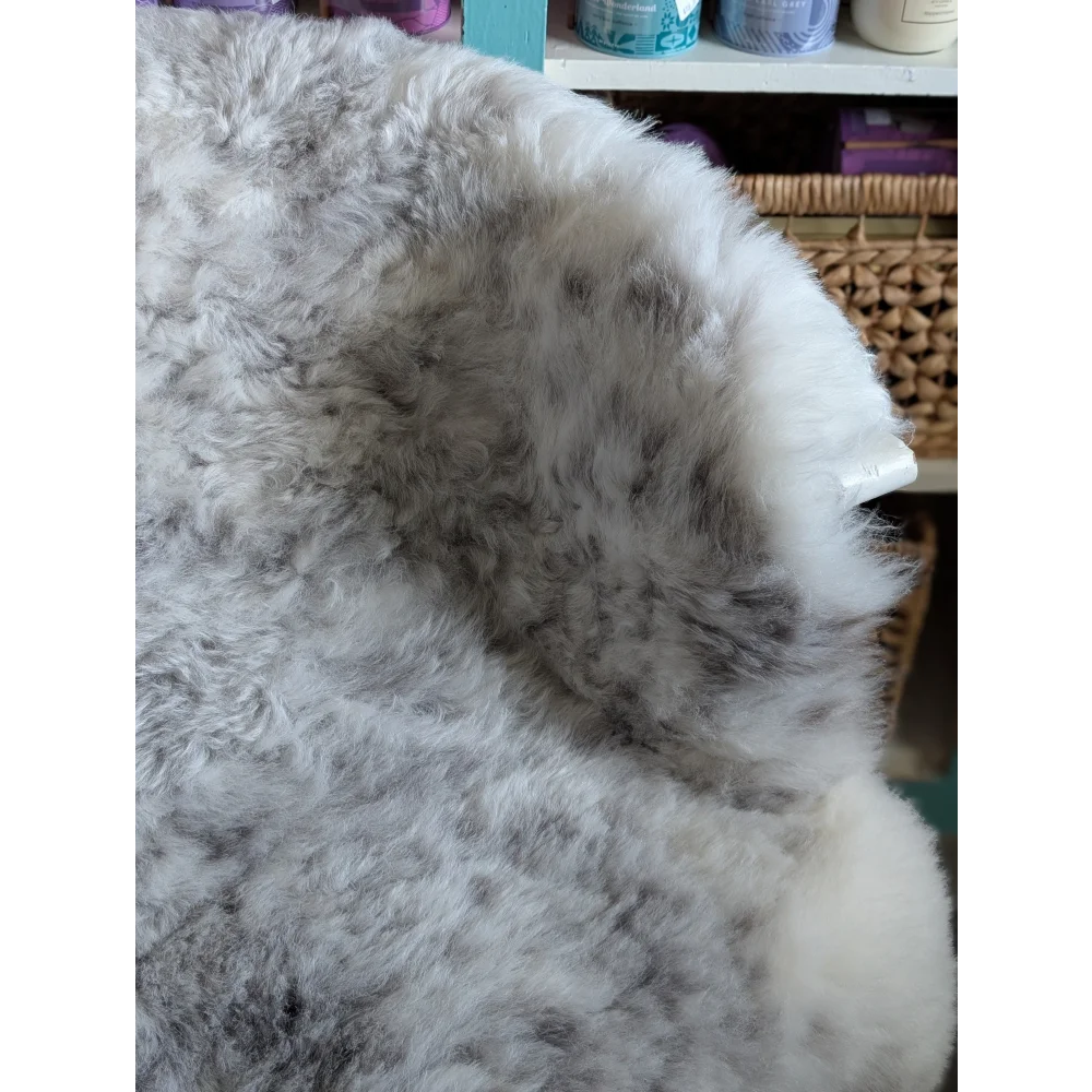 A plush fluffy gray and white large spotted icelandic sheepskin rug with soft natural texture made of short wool