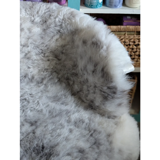 A plush fluffy gray and white large spotted icelandic sheepskin rug with soft natural texture made of short wool