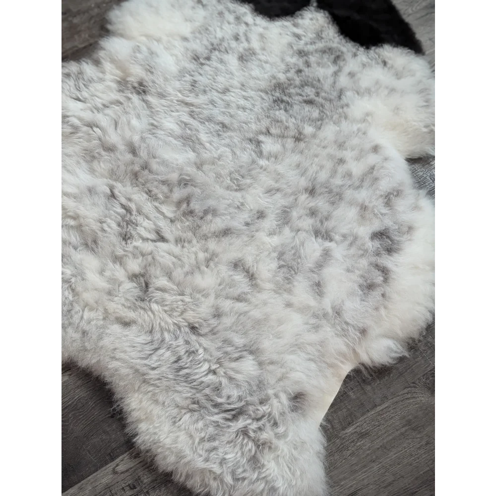 A soft large icelandic sheepskin rug with a fluffy medium spotted white and gray natural wool pattern