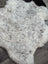 A soft large icelandic sheepskin rug with a fluffy medium spotted white and gray natural wool pattern